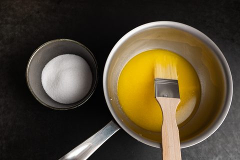 Backpinsel mit Naturborsten in flüssiger Butter, daneben Zucker
