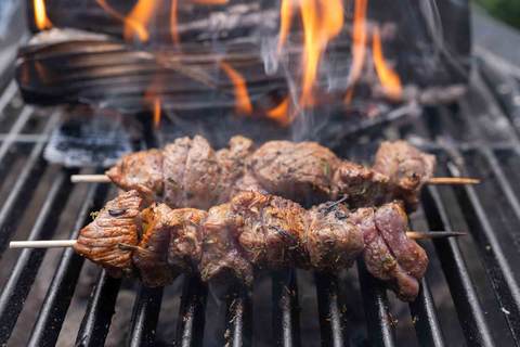 Fleischspieße auf dem Grill mit offener Flamme und Rauchentwicklung