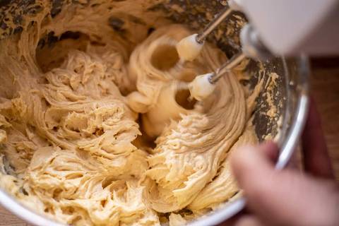 Handrührgerät verrührt hellen Kuchenteig in einer Schüssel
