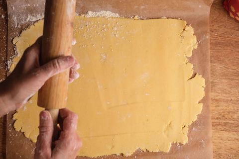 Mürbeteig wird mit einem Rundholz ohne Griffe ausgerollt
