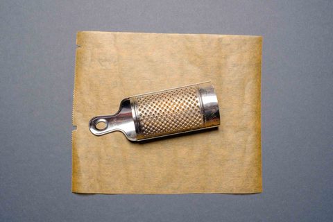Kleine Muskatreibe aus Metall auf Backpapier
