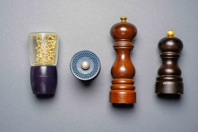 Vier Pfeffermühlen, zwei aus Holz, eine mit Glaskörper und eine kleine runde Mühle
