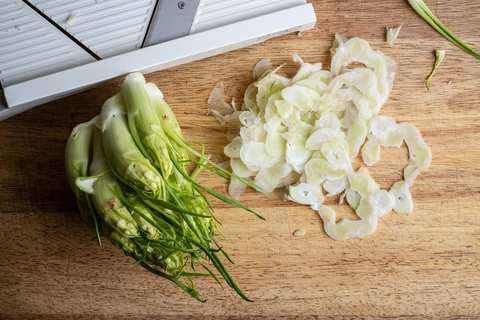 Puntarelle-Sprossen fein gehobelt auf dem Holzbrett