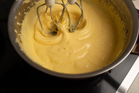Rührbesen schlagen eine hellgelbe Sauce im Topf auf