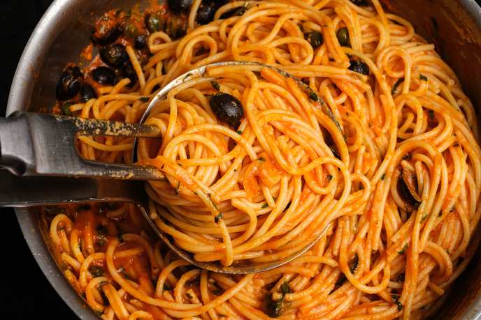 Spaghetti in Tomatensoße werden mit Schöpfkelle und Fleischgabel angerichtet