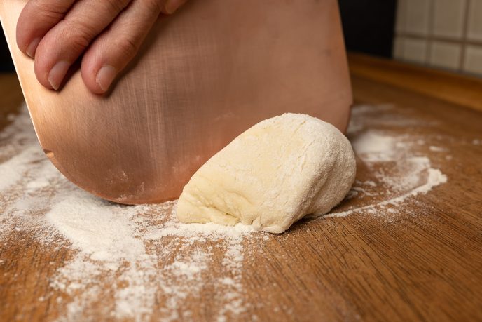 Pizzateig wird auf der bemehlten Arbeitsfläche mit der Teigkarte portioniert