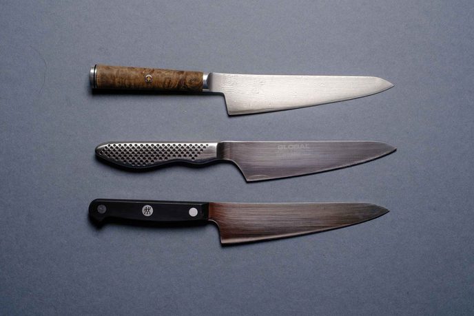 Drei Kochmesser untereinander, mit Holzgriff, mit Edelstahlgriff und mit schwarzem Griff