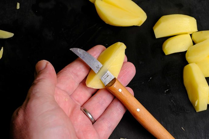 Tourniermesser mit gebogener Klinge beim Tournieren einer Kartoffel