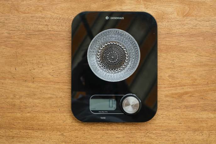 Digitale Küchenwaage mit einer Glasschüssel auf dem Holztisch