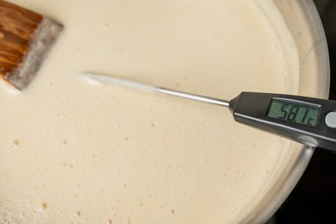 Digitales Thermometer in einer hellen Vanillecreme im Topf